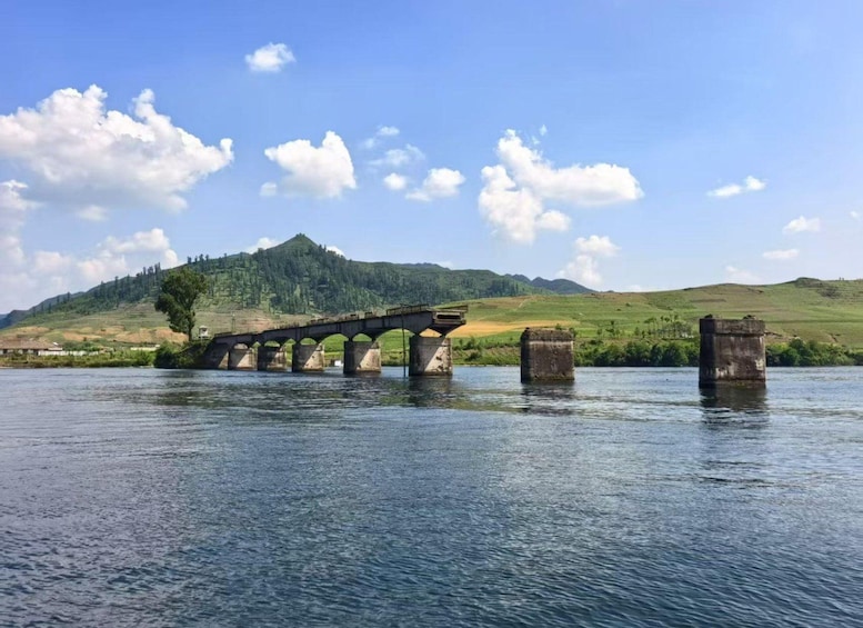 A stone bridge over a river with hills in the background. 3