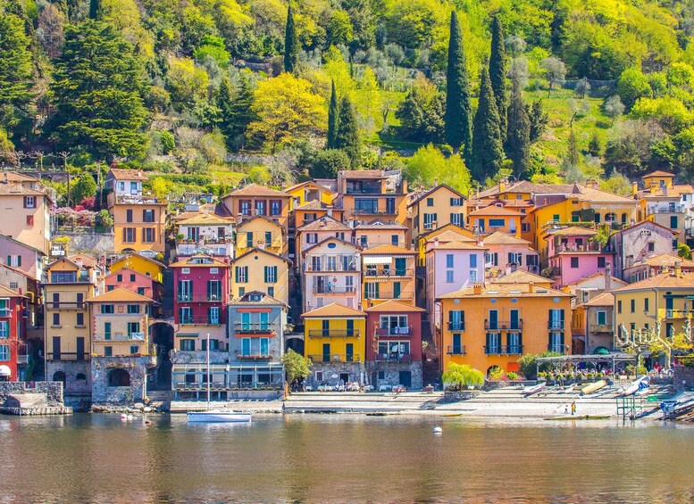 A colorful coastal village with terracotta-roofed buildings, a calm waterfront, and lush greenery in the background. 1
