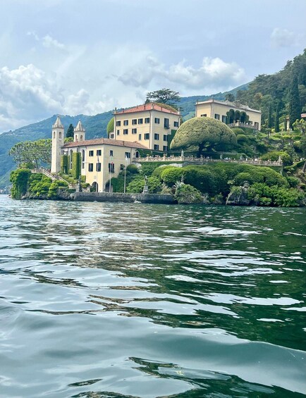 A lakeside villa with a tower, surrounded by lush greenery and hills. 4