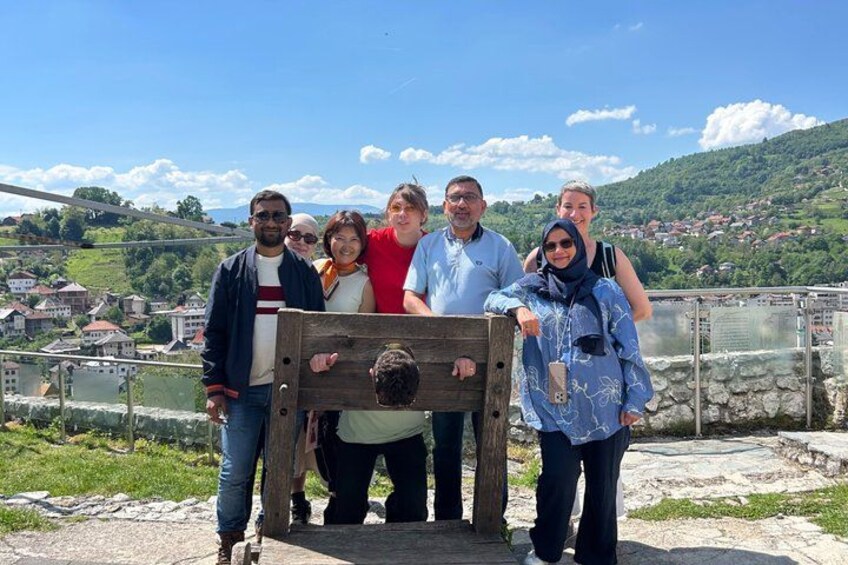 A group of people standing on a bridge with a scenic view of a river and hills in the background. 5