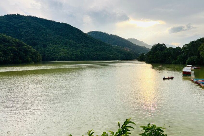 A calm river with a boat, surrounded by lush green hills and a small house on the right. 2