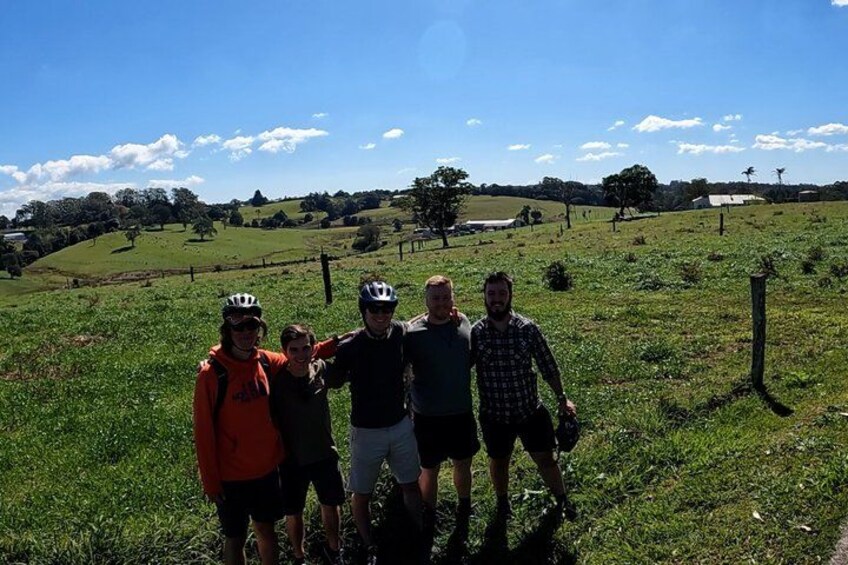 A group of people standing in a grassy field with a hilly landscape in the background. 5