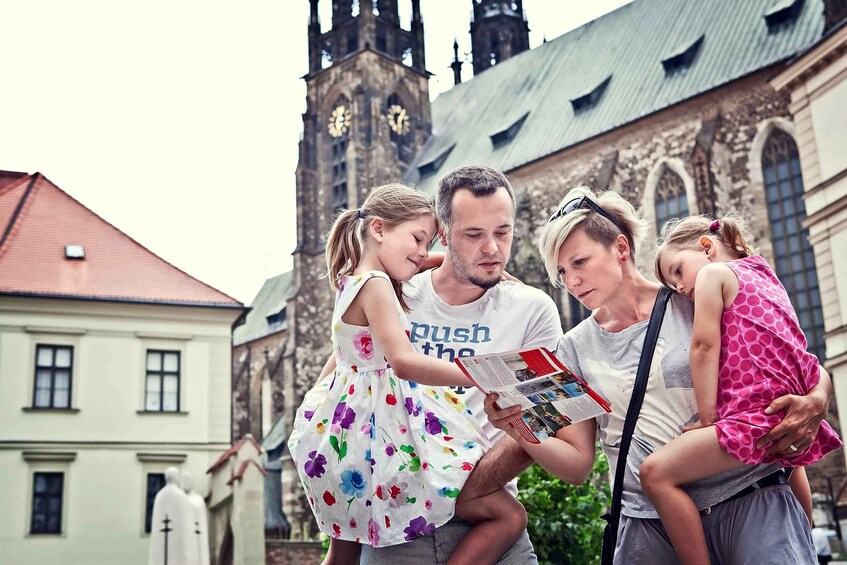 Eine vierköpfige Familie vor einer historischen Kirche mit einem Glockenturm. 5