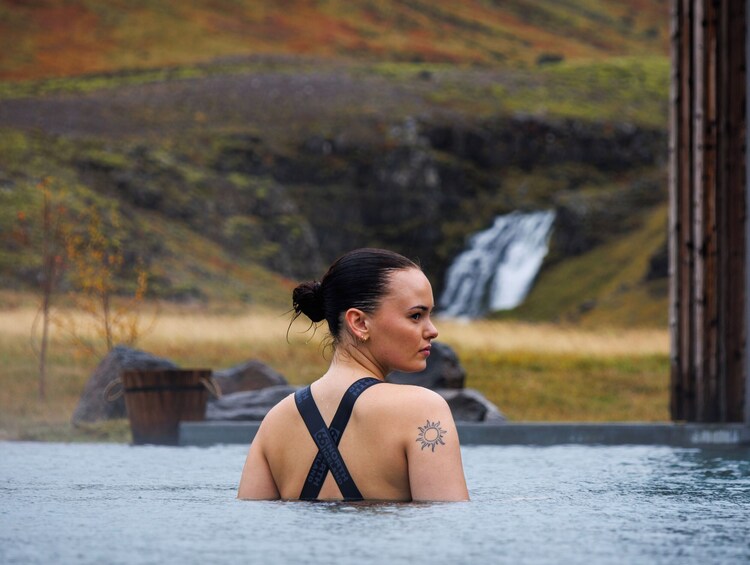 Una persona en aguas termales, con una cascada al fondo. 1