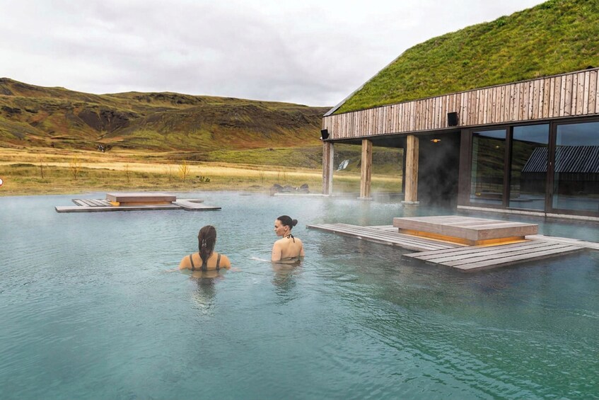 Un spa geotérmico con pasarelas de madera sobre un manantial termal, rodeado de un paisaje montañoso. 4