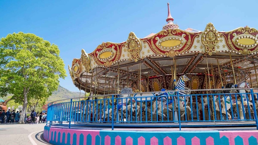 A carousel with ornate golden decorations and a blue fence. 2
