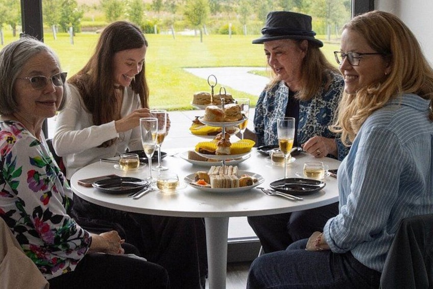 Four people sitting at a round table with food and drinks. 2