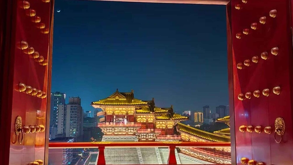 A traditional Chinese building at night with illuminated details, viewed through a red-framed window. 3