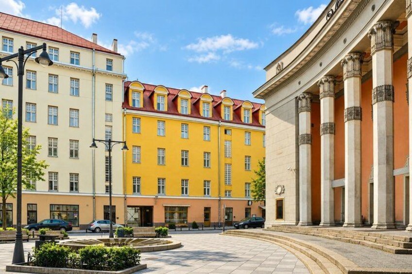 A city square with colorful buildings, a fountain, and a classical building with columns. 4
