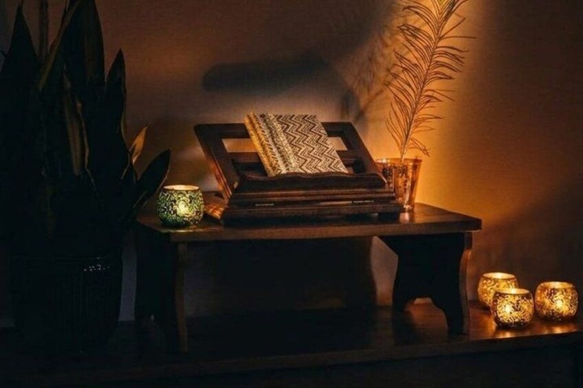 A dimly lit room with a typewriter, a patterned cushion, and a potted plant. 2
