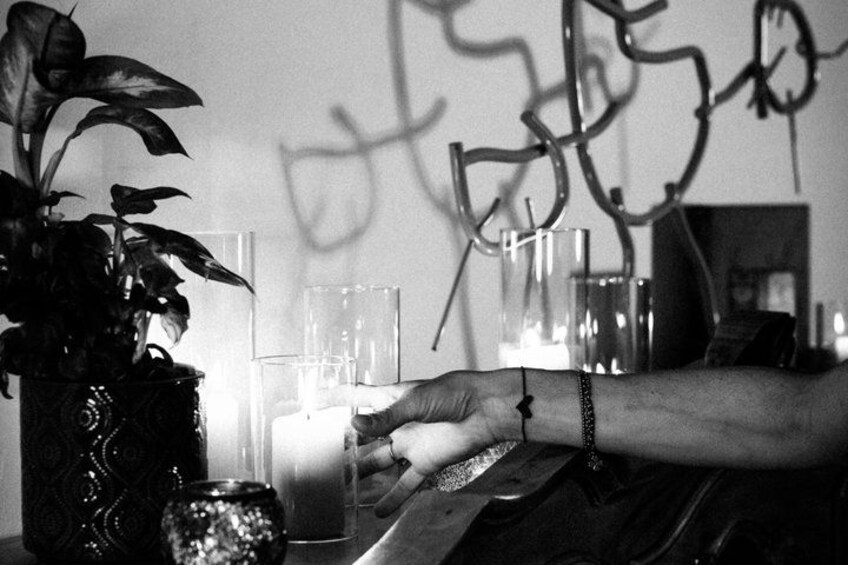 A person lighting candles in a room with a potted plant and clear glass containers. 5