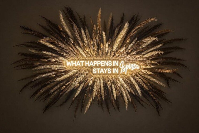 A wheat field with a neon sign that reads 'WHAT HAPPENS IN Ibiza STAYS IN Ibiza.' 1