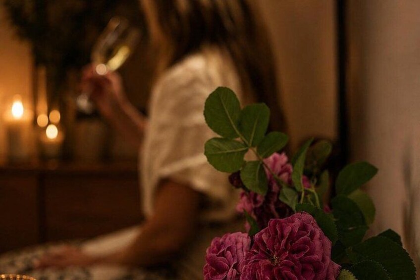 A person holding a wine glass, a table with a vase of flowers, and a dimly lit room with candles. 4