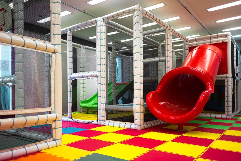 A play area with a red slide, a green slide, and a climbing structure. 3