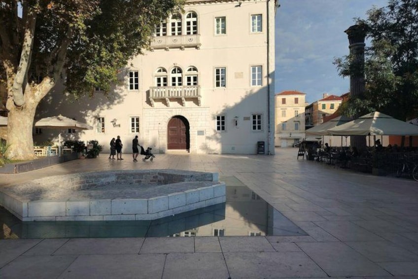 A courtyard with a fountain, a building with arched windows, and outdoor seating. 4
