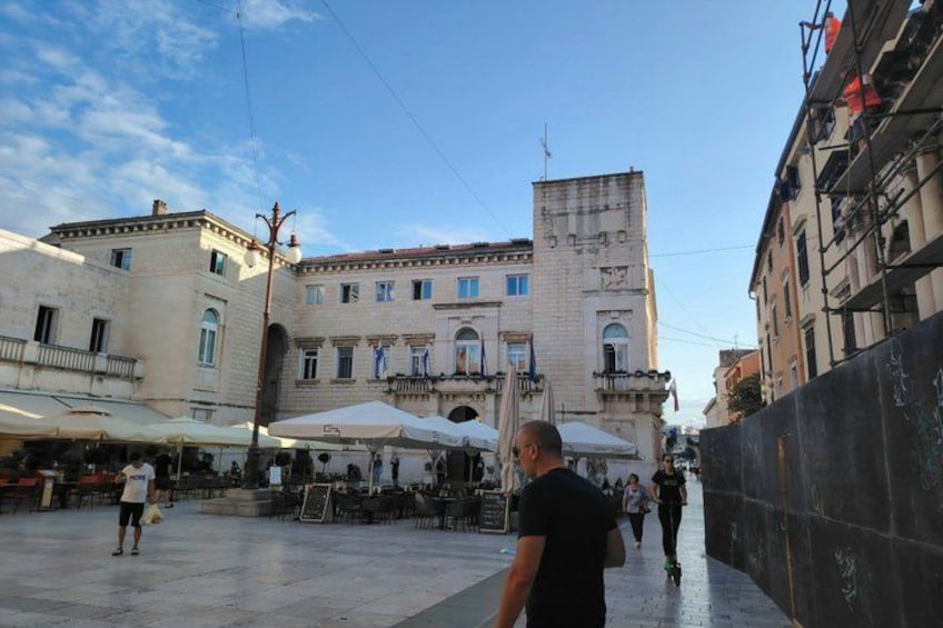 A square with outdoor cafes, a historic building, and a pedestrian walkway. 3