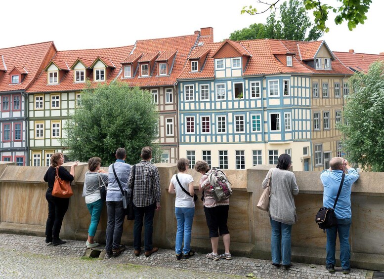 A group of people standing on a bridge, looking at colorful half-timbered buildings. 2