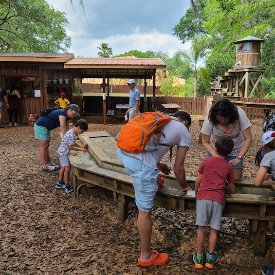 People interacting with a wooden structure in a park with trees and a wooden building in the background. 3