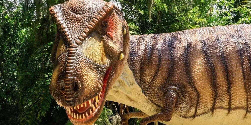 A large dinosaur model with a textured skin pattern, set against a backdrop of dense green foliage. 2