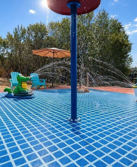 A water fountain with a blue tiled floor, a green crocodile toy, and a blue chair. 4