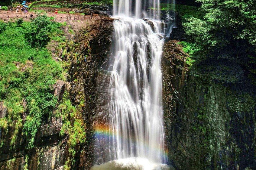 A waterfall cascading down a rocky cliff surrounded by lush greenery. 1