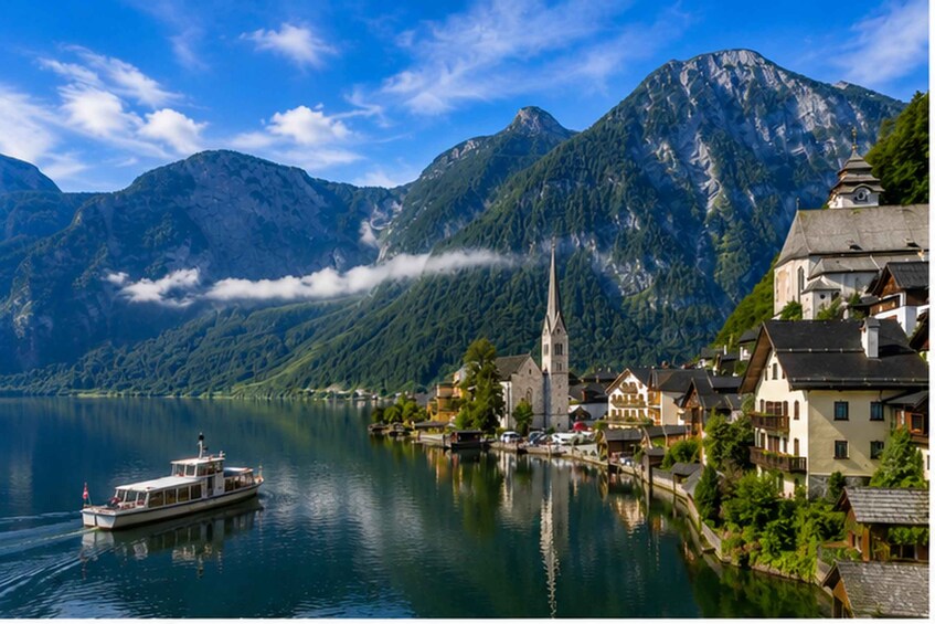 A lake with a boat, a church, and mountains in the background. 1