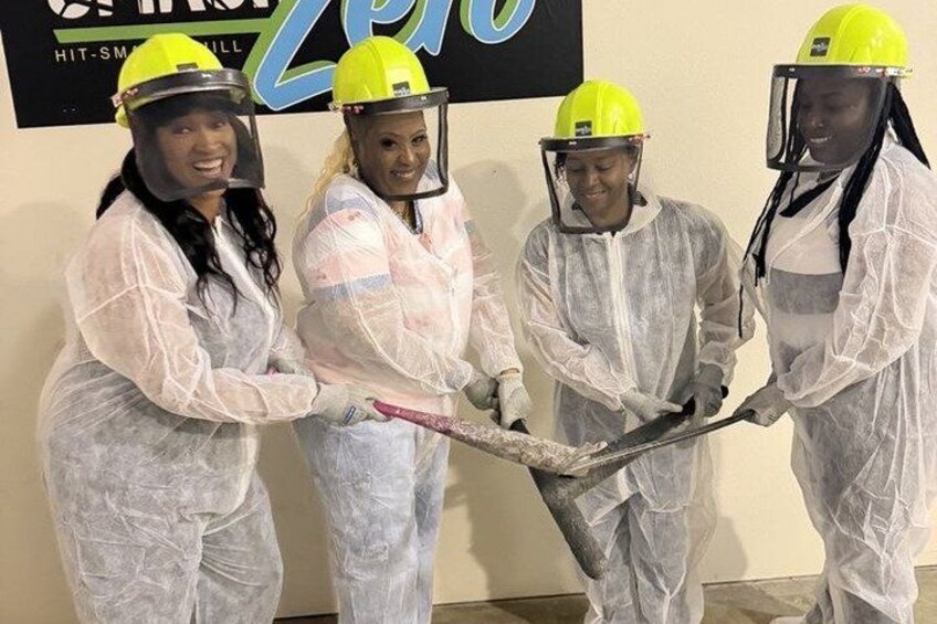 Four people in protective suits and helmets holding a large tool. 1