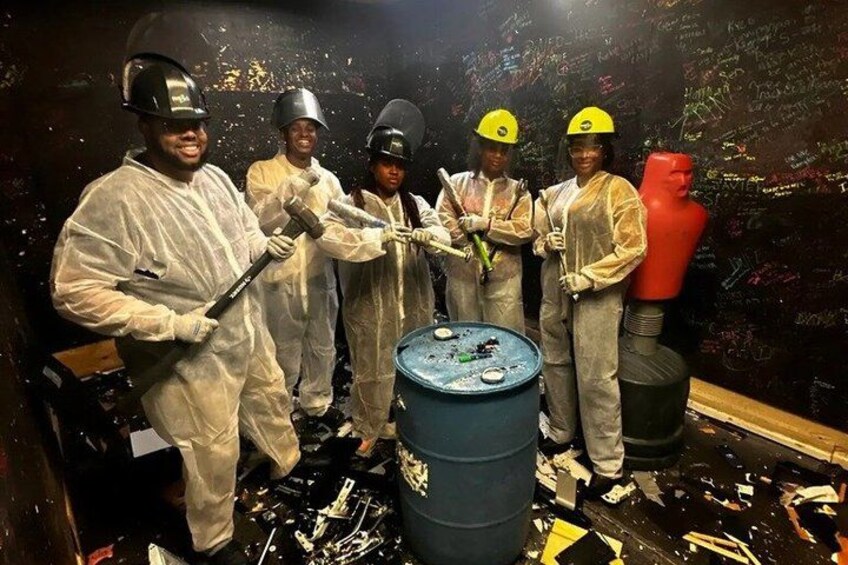 A group of people in protective gear painting a large blue barrel. 1