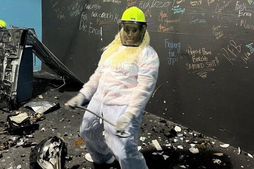 A person in protective gear standing in a debris-filled area with graffiti on the wall. 4