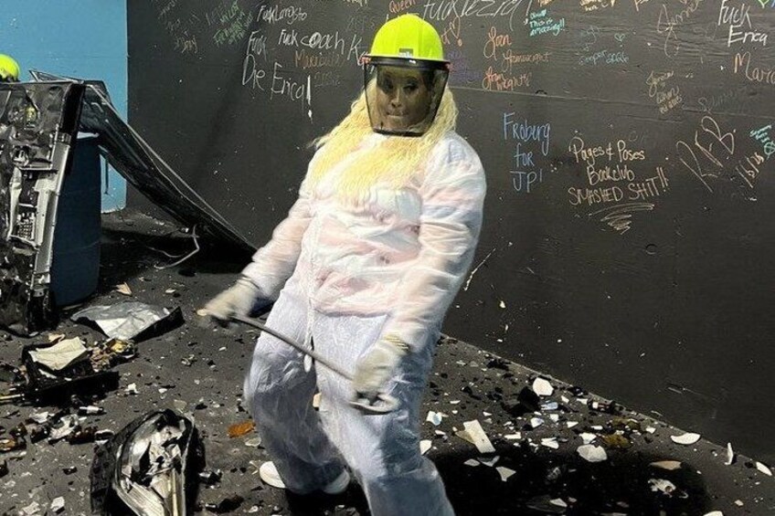 A person in protective gear cleaning debris from a damaged wall with graffiti. 2
