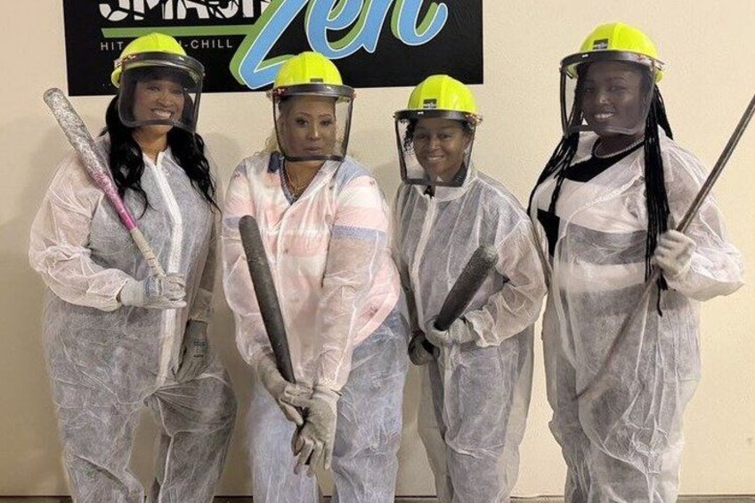 Four people in protective suits and helmets holding tools, standing in front of a sign. 3