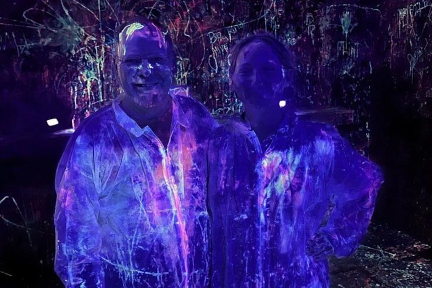 Two people standing in a room with colorful graffiti on the walls. 5
