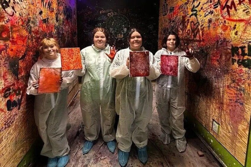 Four people in protective suits holding red panels in a graffiti-covered hallway. 1