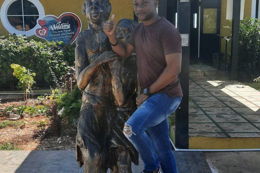 A man posing with a bronze statue of a man and a child. 3