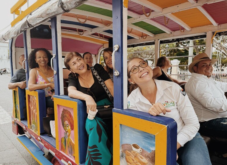 A colorful trolley with passengers, featuring artwork on the sides. 2
