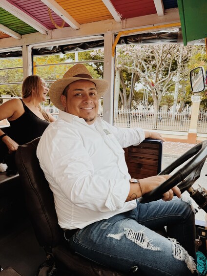 A person driving a vehicle with a steering wheel, wearing a white shirt and a straw hat. 5