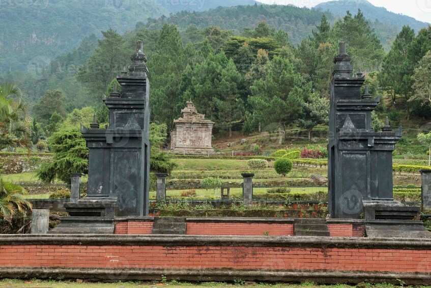 A cemetery with stone monuments and a lush green landscape. 1