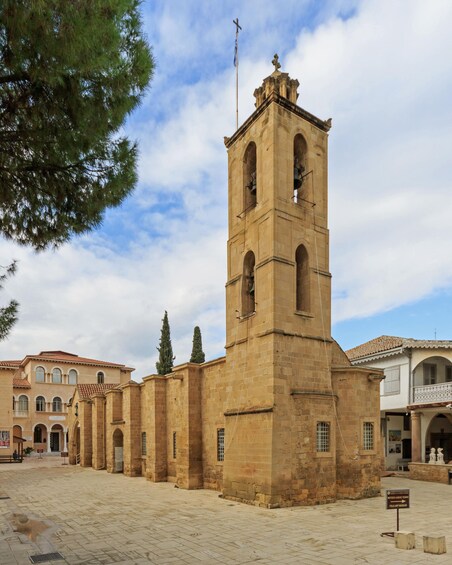 A historic church with a bell tower, surrounded by traditional buildings and a clear sky. 3