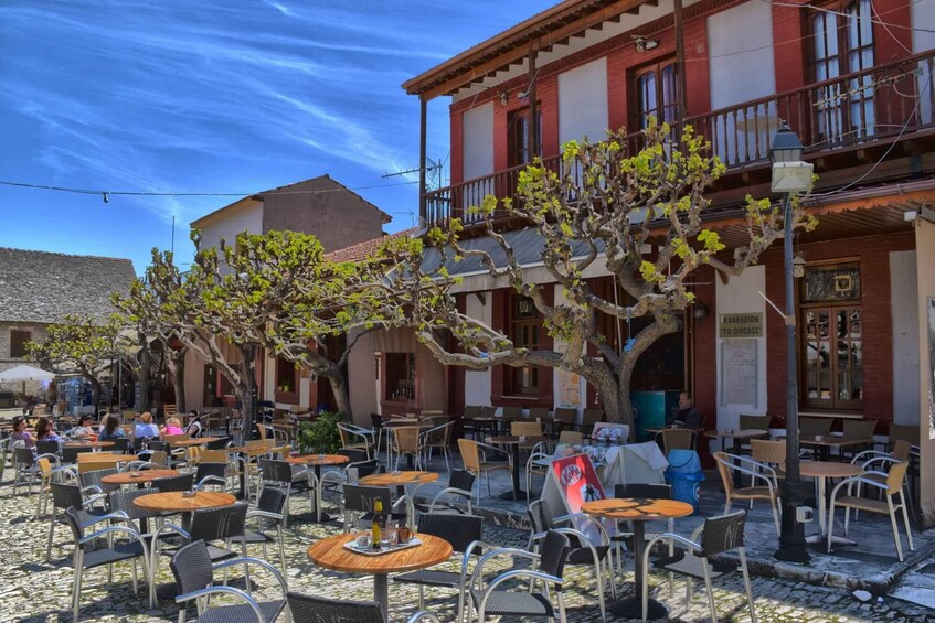 A cobblestone street with outdoor seating and trees. 4