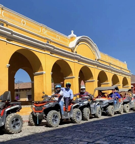 A row of ATVs parked in front of a yellow building with arches. 5