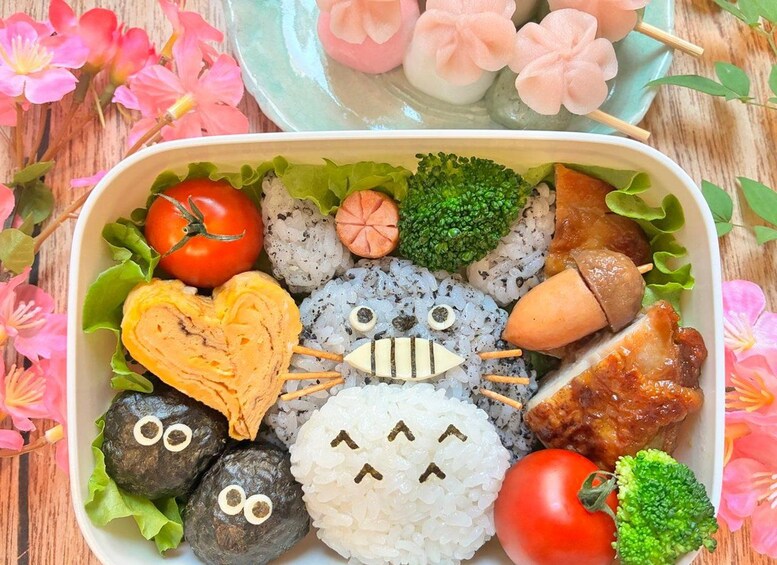 A bento box with various food items including sushi, rice, vegetables, and decorative elements. 1