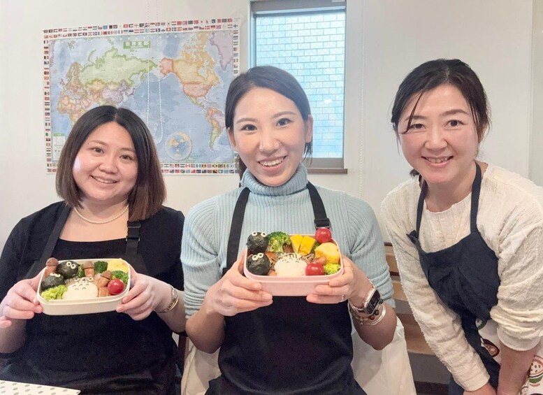 Three individuals holding bento boxes with various food items. 5
