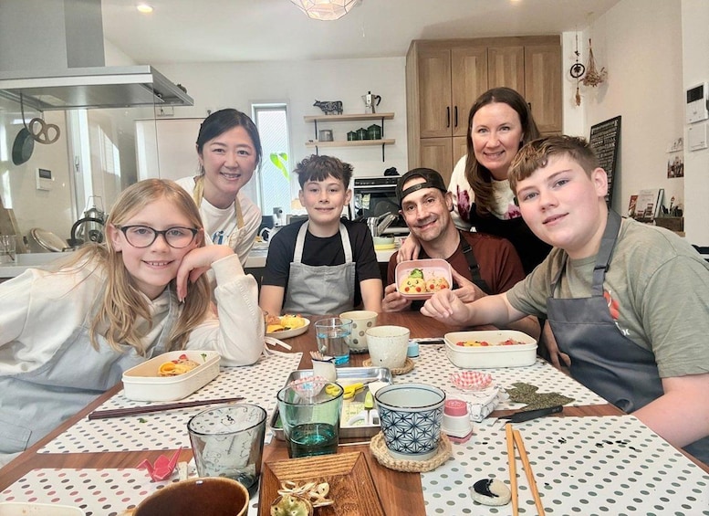 A group of people sitting at a table with food and drinks, in a kitchen setting. 4