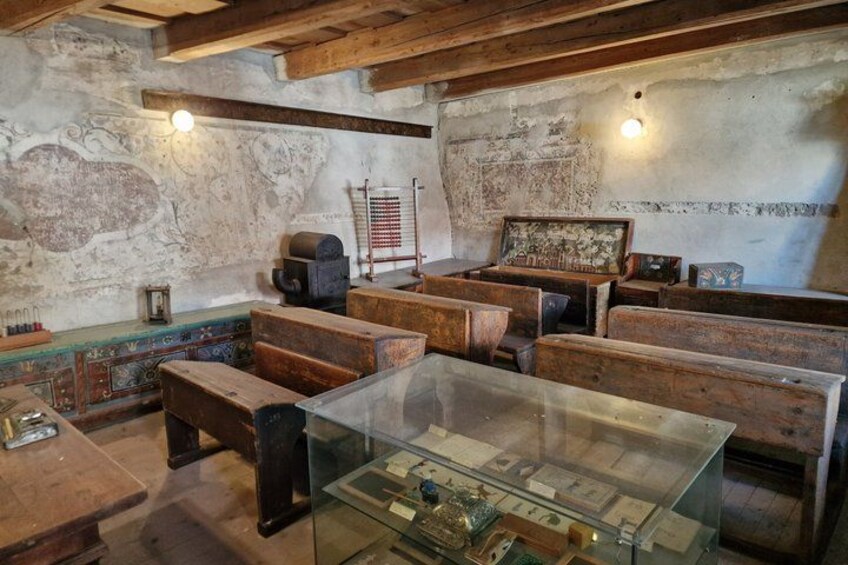 A room with wooden benches, a glass display case, and a wall with decorative elements. 5