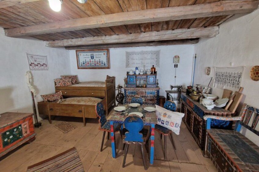 A rustic room with a wooden bed, a table with chairs, and various decorative items. 2