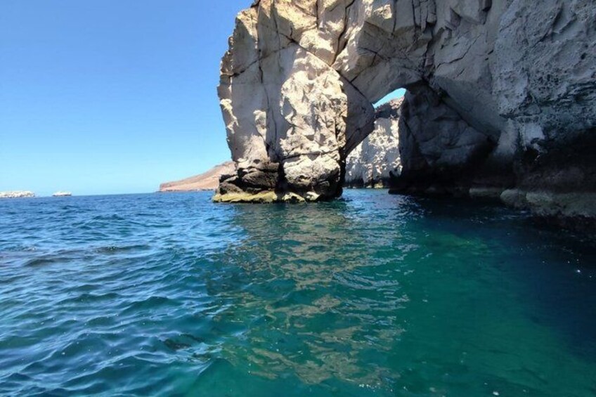 A coastal rock formation with clear blue water. 4