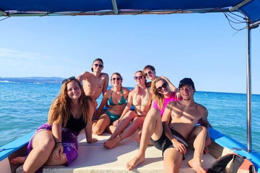 A group of people on a boat with a clear blue sky and calm sea in the background. 1