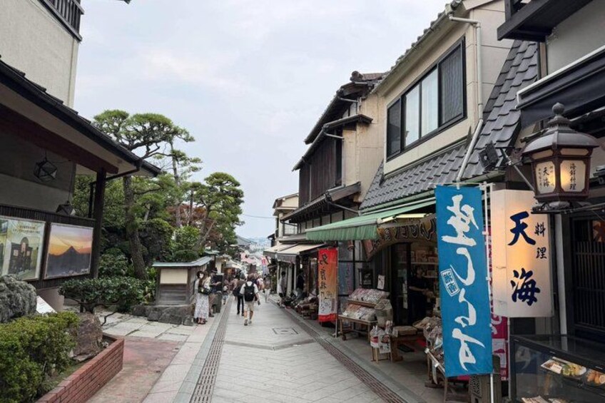 A narrow street lined with traditional buildings, a blue sign with Japanese characters, and a shop with a lantern. 1