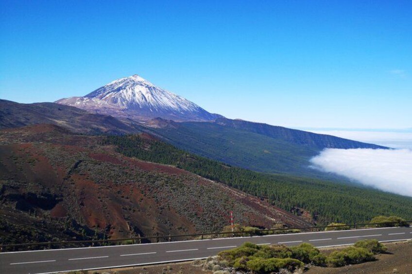 A snow-capped mountain, a road, and a forested valley. 2