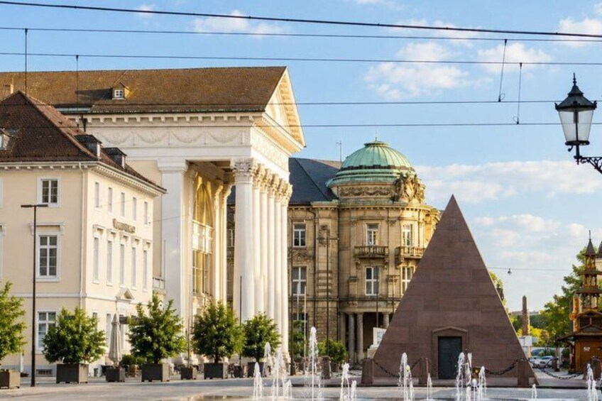 A historic building with classical architecture, a large triangular monument, and a fountain in the foreground. 5